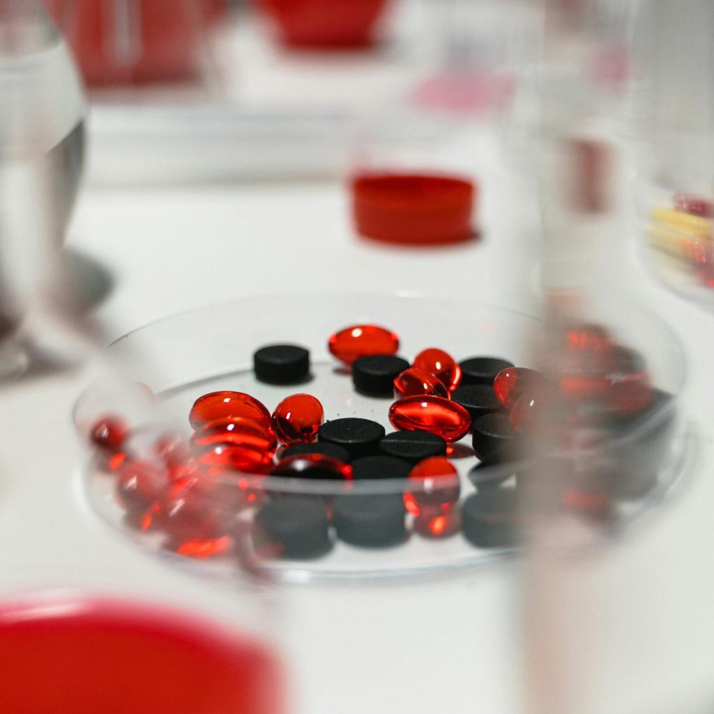 pexels photo 7230326 7230326 Close-up view of red and black pills on a lab table with blurred background.